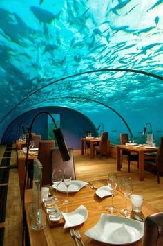 an underwater restaurant with tables and chairs under the water