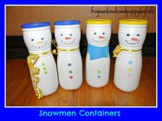 four snowmen containers sitting on top of a wooden table next to each other with gold ribbon around them