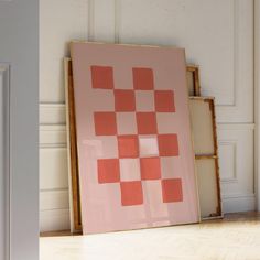 a pink and orange painting sitting on top of a hard wood floor next to a white wall