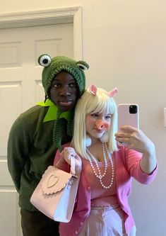 a man and woman in costume taking a selfie with a cell phone while standing next to each other