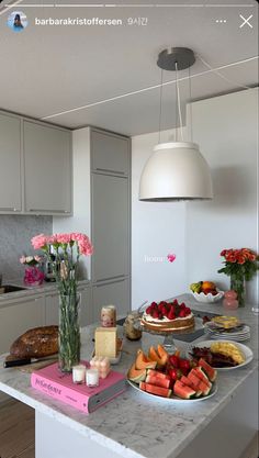 a kitchen counter topped with plates and bowls filled with fruit on top of it next to a light fixture