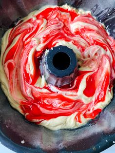 a red and white swirl cake batter in a pan with a black plastic ring on top