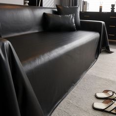 a pair of sandals sitting on the floor next to a black leather couch in a living room