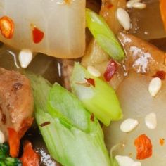 a close up view of vegetables and meat with nuts on them, including broccoli