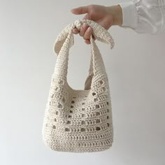 a crocheted purse being held by a person's hand on a white background