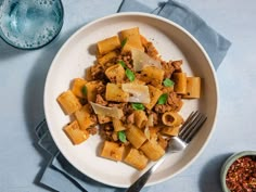 a white plate topped with pasta and meat next to a bowl of chili seasoning