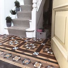 an entryway with stairs and tiled flooring next to potted plants on the steps