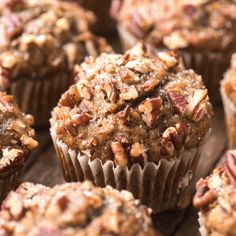 there are many muffins that are on the wooden table and one has pecans in it