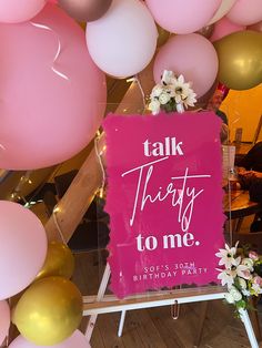 a pink sign that says talk thirty to me surrounded by balloons and flowers in the background