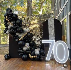 the number 70 is made out of balloons and beads in front of a building with trees