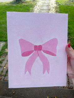 a hand holding up a card with a pink bow on it