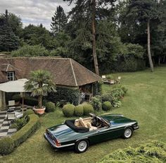 a green car parked in front of a house on top of a lush green field