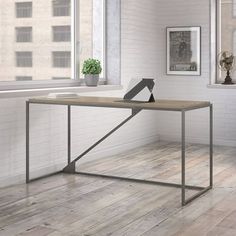 an office desk in front of a window with a potted plant on the table