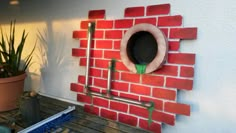 a red brick wall with pipes and a hole in the middle that is made out of bricks