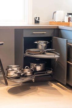 an open kitchen cabinet with pots and pans in it