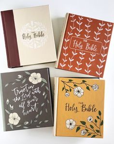 four different colored notebooks with hand lettering on the front and back covers, all lined up together