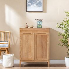 a wooden cabinet sitting next to a potted plant on top of a hard wood floor