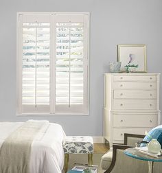 a bedroom with blue walls and white shutters on the window sill is shown