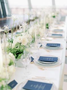 the table is set with white flowers and blue place settings for dinner guests to enjoy