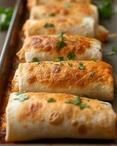 several burritos are lined up on a baking sheet and ready to be eaten