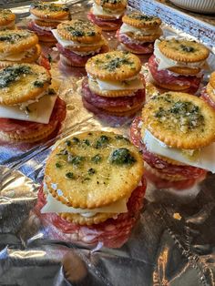 several sandwiches on tin foil with cheese and toppings in the middle are ready to be eaten