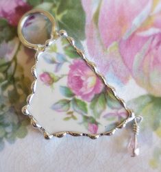 a close up of a key chain on a flowered cloth with flowers in the background