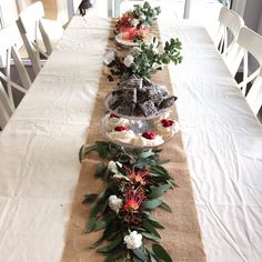 a long table is set with cupcakes, flowers and greenery on it