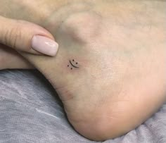 a woman's foot with a small smiley face tattoo on the left side of her toe