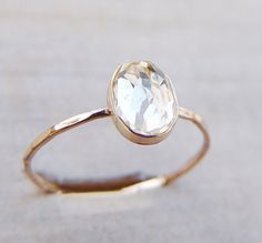 a gold ring with a faceted white diamond sitting on top of a wooden surface