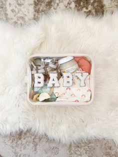 a baby gift box on top of a fluffy white blanket with the word baby written in it