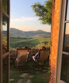 two people lounging on lawn chairs in front of an open door to a vineyard