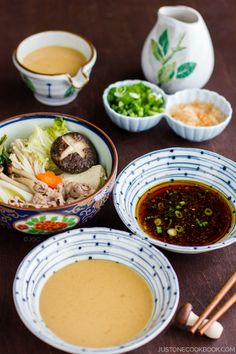 three bowls of soup with chopsticks on the table next to them and two cups of soup