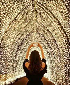 a woman standing in the middle of a tunnel filled with lights