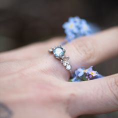 a person's hand holding a ring with flowers on it