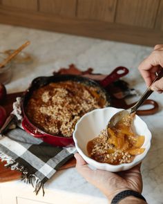 a person holding a spoon over a bowl of food on top of a kitchen counter