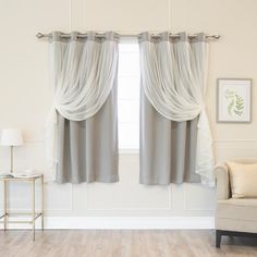 a living room with white walls and two windows covered in gray drapes next to a chair