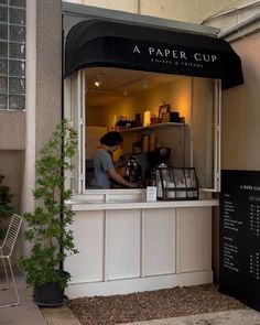 a small coffee shop on the side of a building with a man working behind it