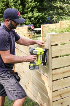 a man is using a driller on a wooden fence