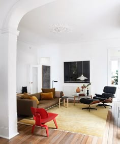 a living room filled with furniture and a chandelier hanging from the ceiling over a wooden floor