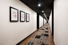 a long hallway with pictures hanging on the wall and carpeted flooring in front of it