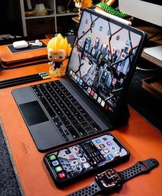 an open laptop computer sitting on top of a desk next to a cell phone and watch