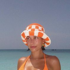 a woman in an orange and white hat on the beach