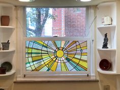 a large stained glass window in the corner of a room with shelves on either side