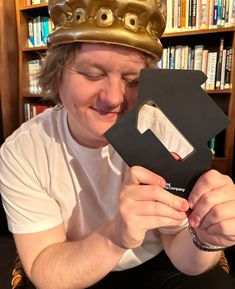 a man wearing a gold crown holding up a black letter shaped like a house with the letter e on it's face