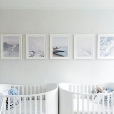 two cribs with pictures on the wall above them in a white nursery room