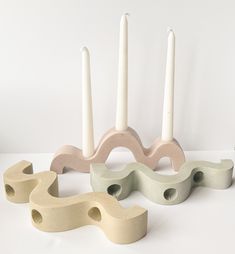 three candles are sitting next to each other in front of some shapes that look like they have been made out of wood