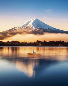 a person in a small boat on the water with a mountain in the back ground