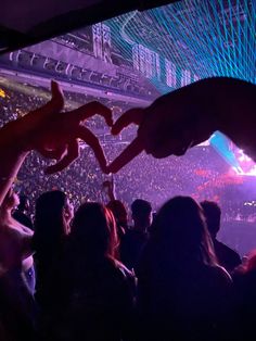 a crowd at a concert with their hands in the air