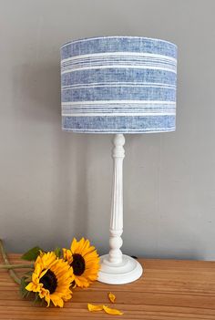 two sunflowers sit on a table next to a lamp