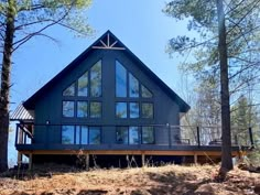 a large blue house sitting on top of a hill in the woods with lots of trees